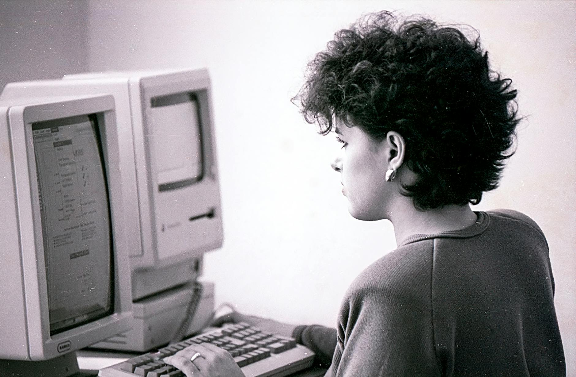 black and white photo of a woman using a vintage computer